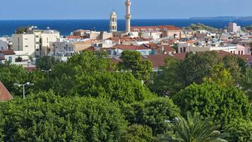 A coastal town with a prominent tower and a dense green area in the foreground.