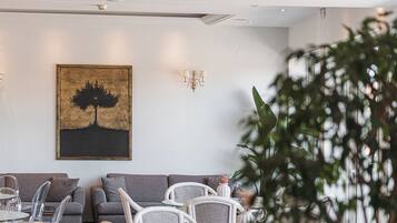 Habitación de hotel con zona de estar, un cuadro en la pared y una planta en maceta.