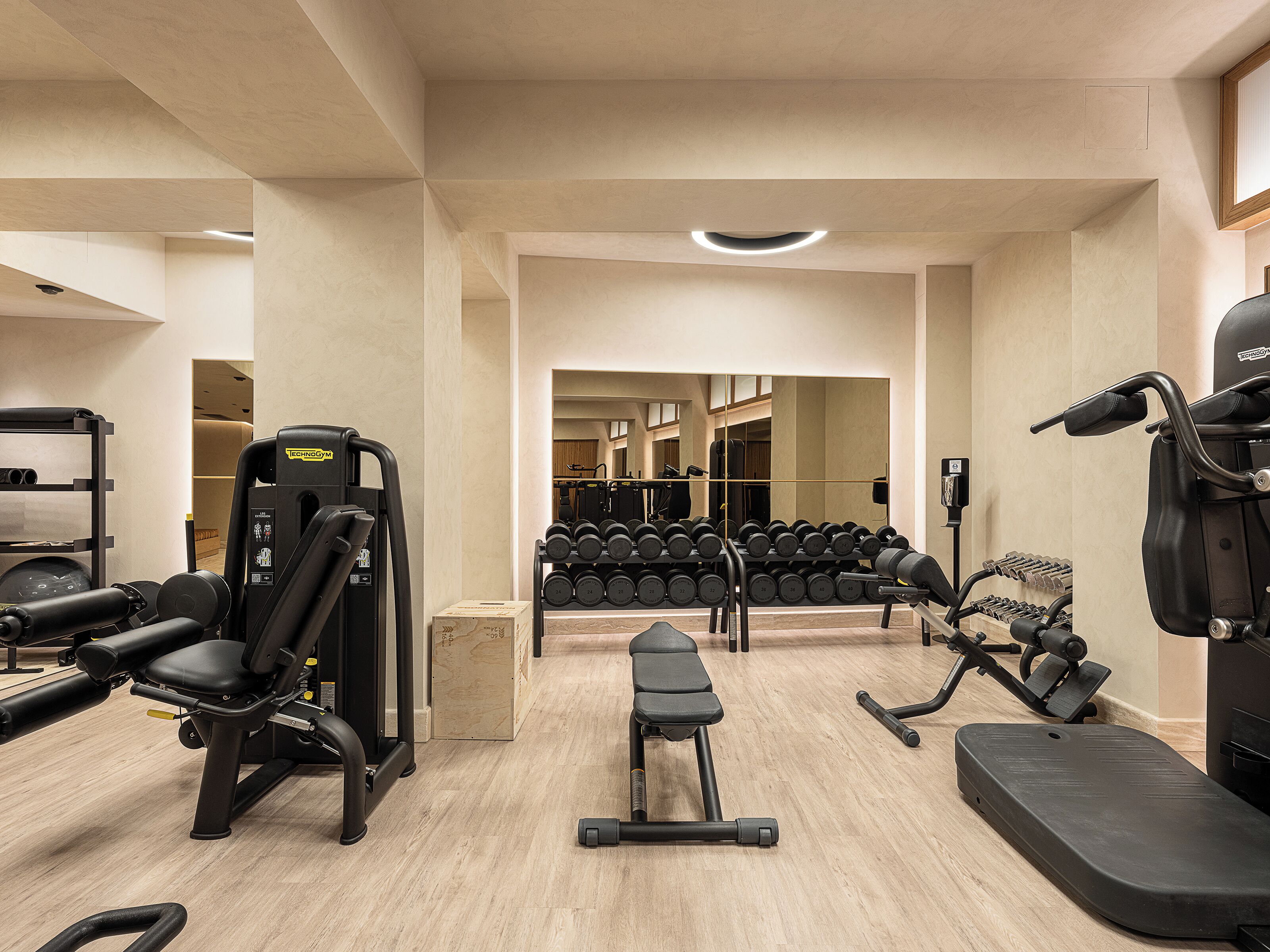 A gym with various exercise equipment including a bench press, dumbbells, and a rowing machine.