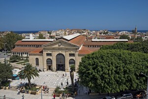 Un edificio histórico con un patio central, rodeado de árboles y una vista despejada del mar.