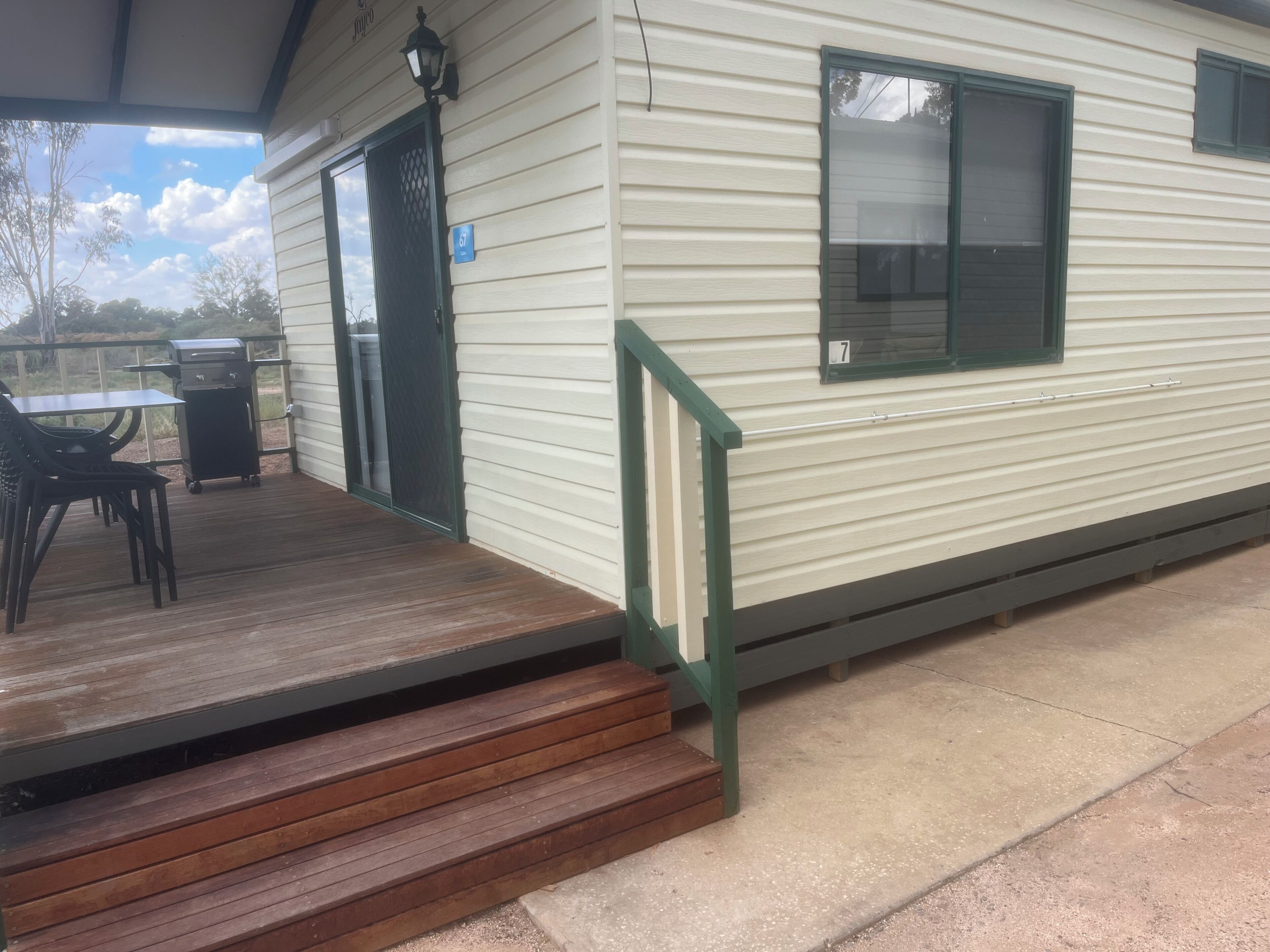 Una casa móvil con una terraza de madera, una parrilla y una mesa de patio.