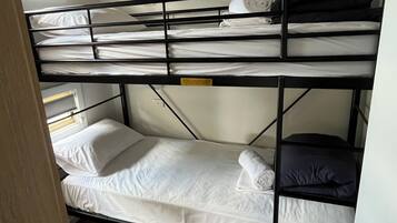 Una cama individual con ropa de cama blanca y un cabecero negro.