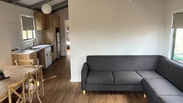Una cucina moderna con mobili in legno, un tavolo da pranzo con sedie e un divano angolare grigio.