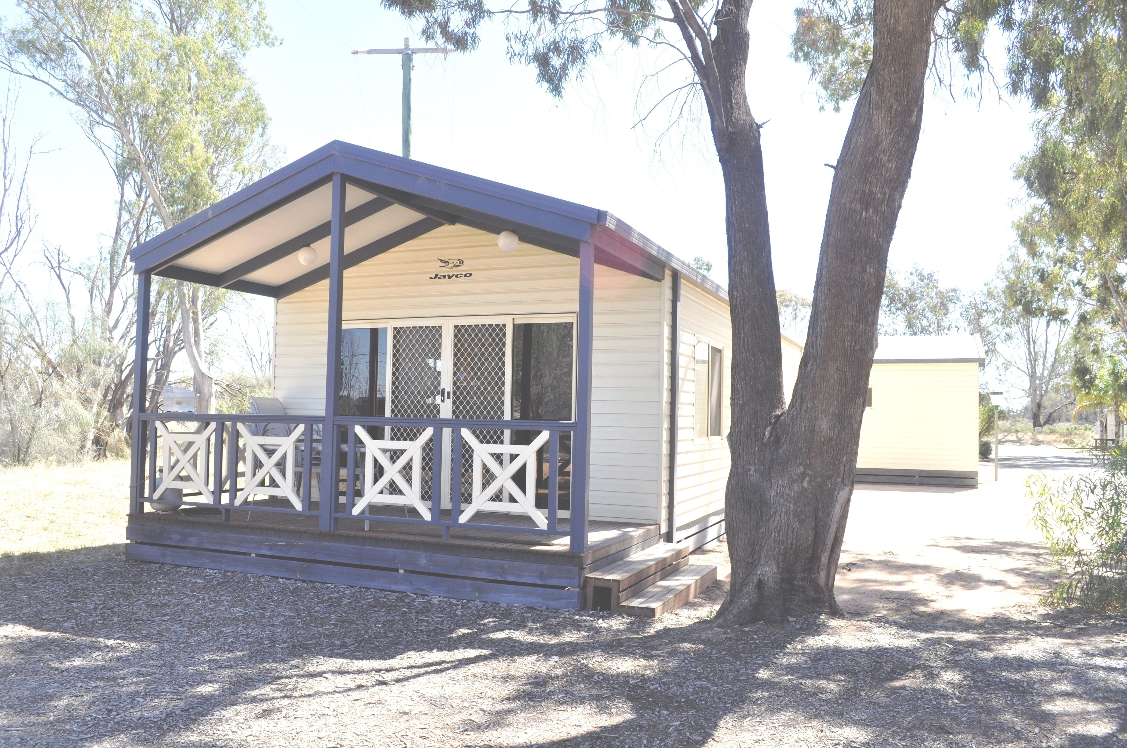 A small, single-story building with a covered porch and a fenced area.
