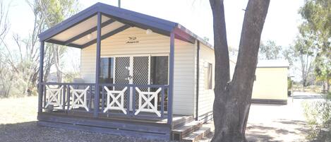 A small, single-story building with a covered porch and a fenced area.