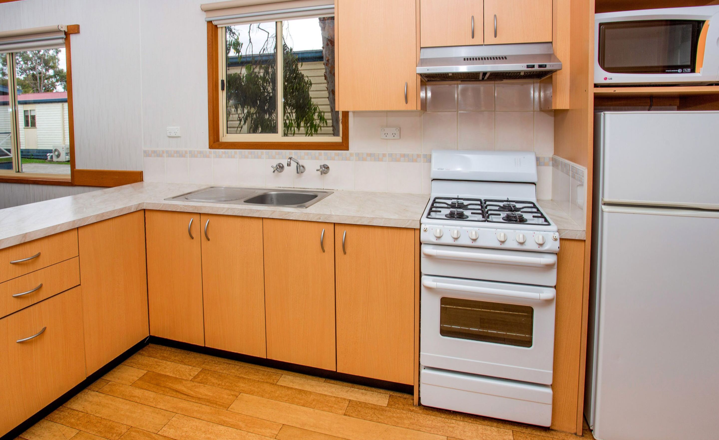 Une cuisine avec des meubles de rangement en bois, un évier, une cuisinière et un four à micro-ondes.