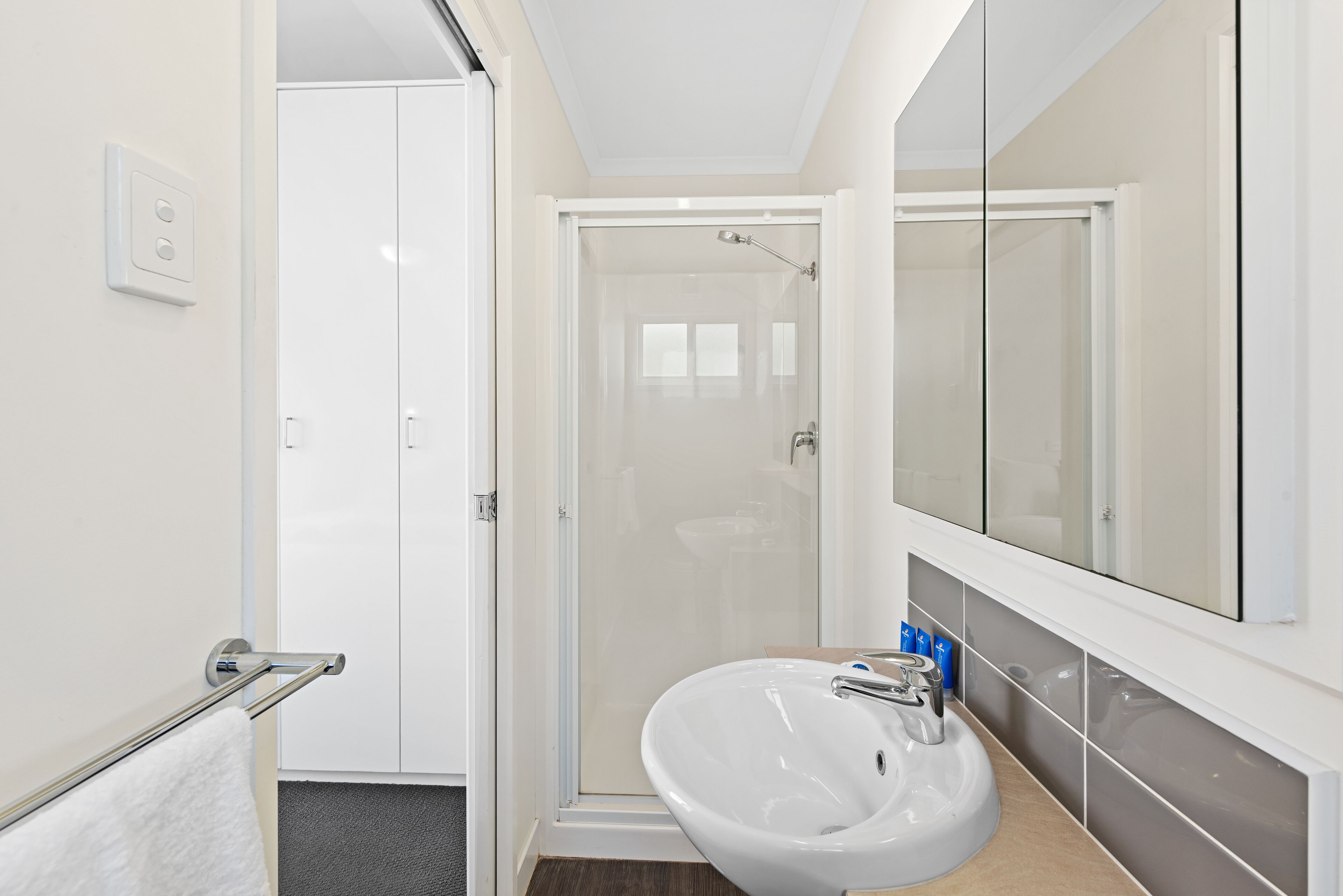 Un baño moderno con cabina de ducha de vidrio, un lavabo blanco y un espejo grande.