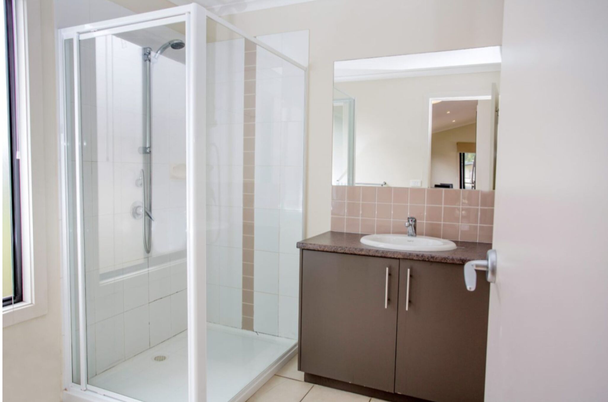 A modern bathroom with a glass-enclosed shower, a sink with a countertop, and a mirror above the sink.