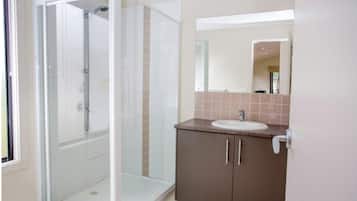 A modern bathroom with a glass-enclosed shower, a sink with a countertop, and a mirror above the sink.