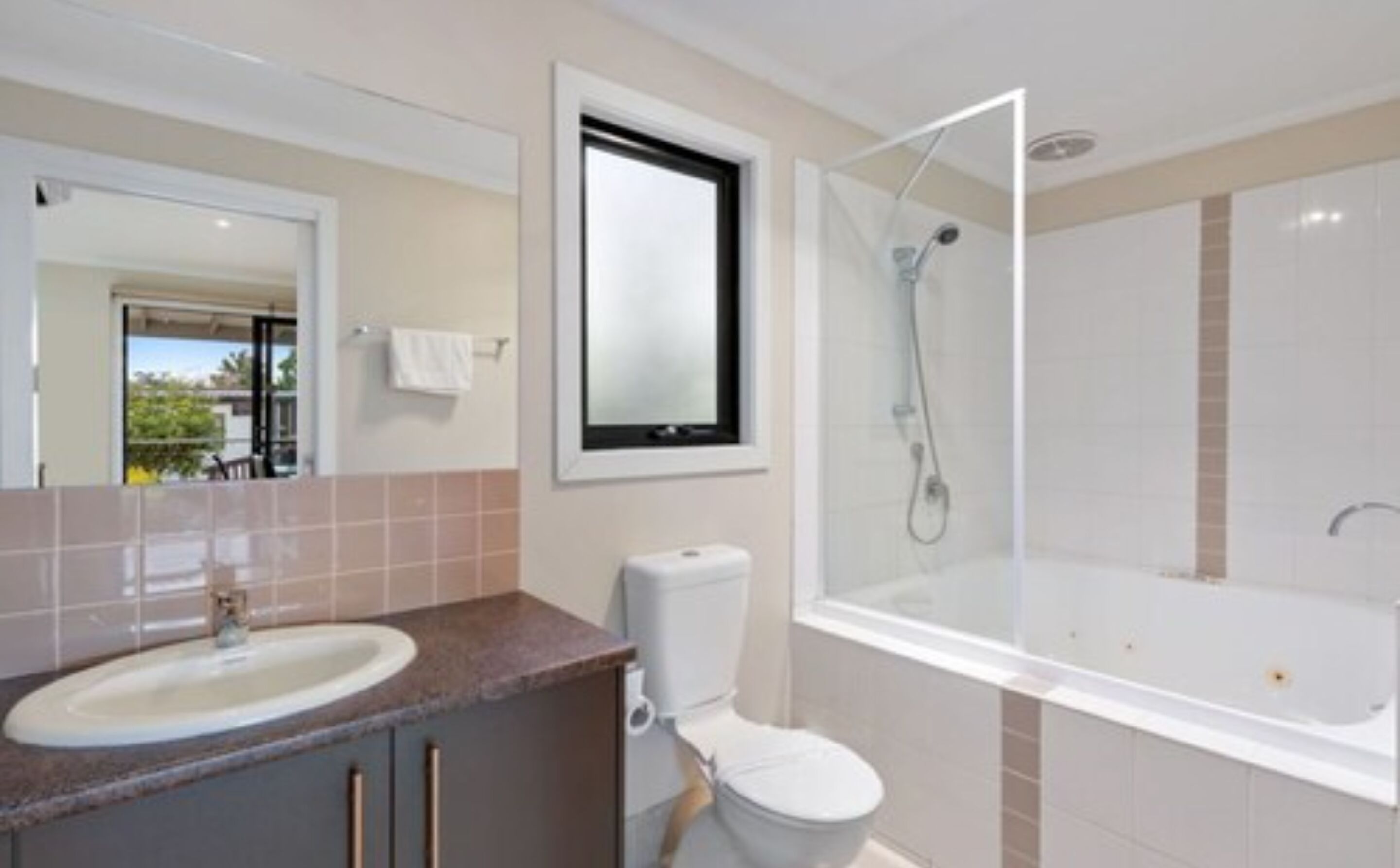 A bathroom with a sink, toilet, and a shower area.