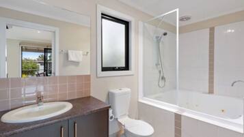 A bathroom with a sink, toilet, and a shower area.