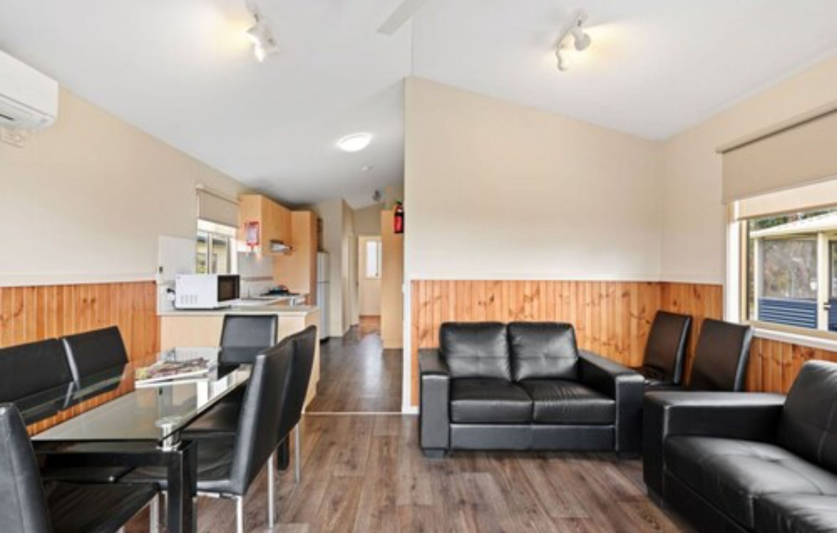 A modern interior with a dining area, a sofa, and a kitchenette.