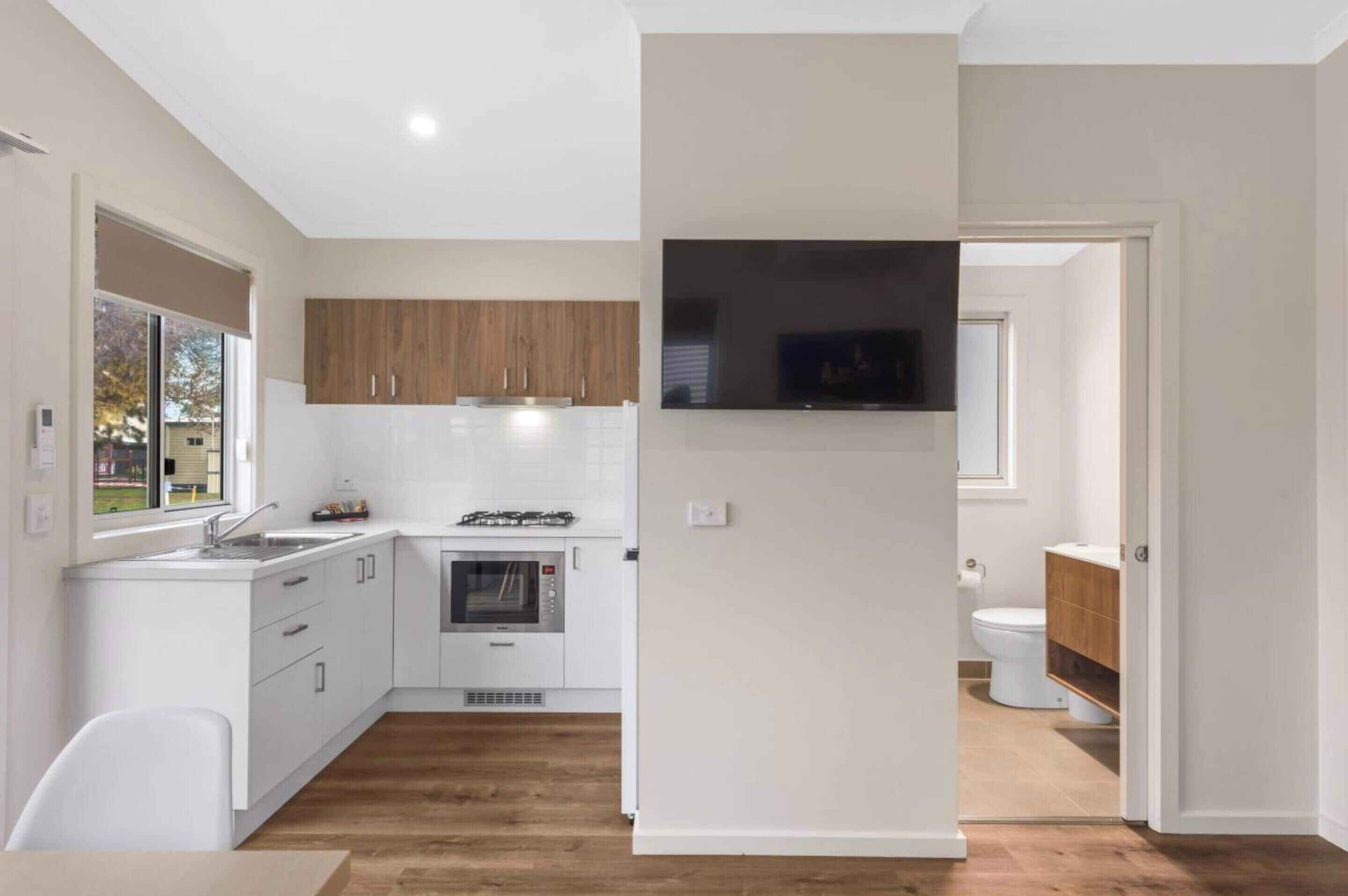 A modern kitchen with white cabinetry, a built-in oven, and a large window.