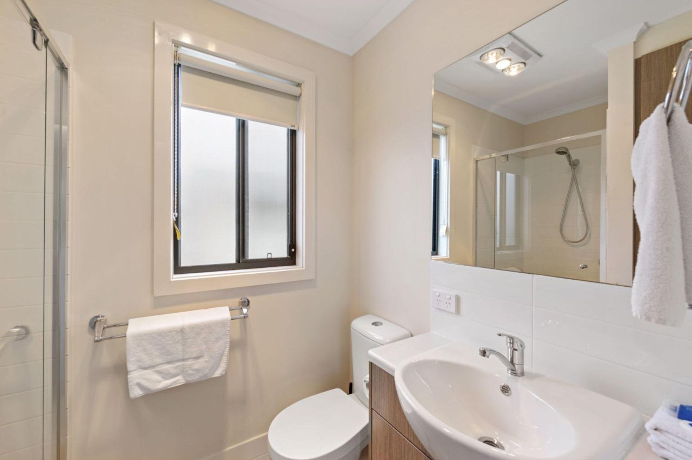 A modern bathroom with a toilet, sink, and shower.