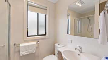 Un baño moderno con inodoro, lavamanos y ducha.