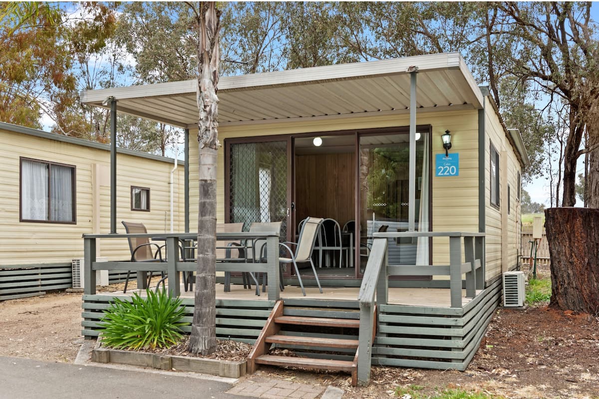A mobile home with a covered porch, outdoor seating, and a number sign indicating 220.