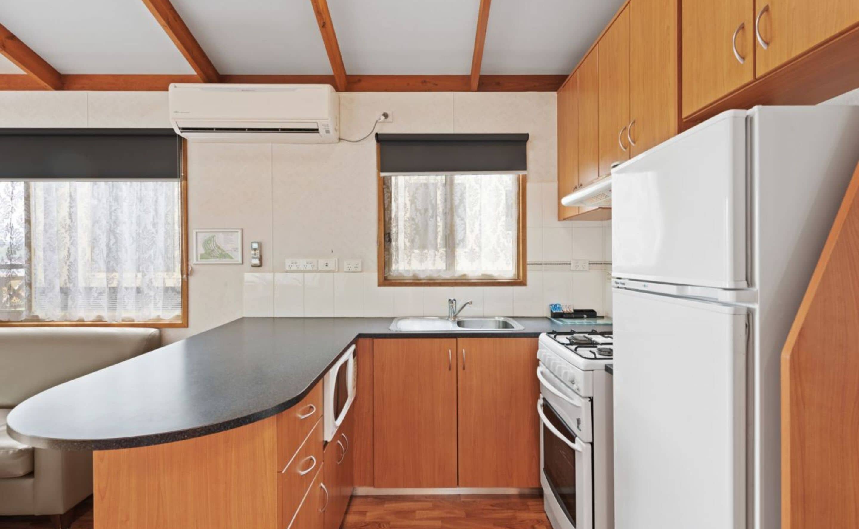 A compact kitchen with wooden cabinets, a white stove, and a refrigerator.