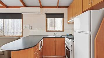 A compact kitchen with wooden cabinets, a white stove, and a refrigerator.