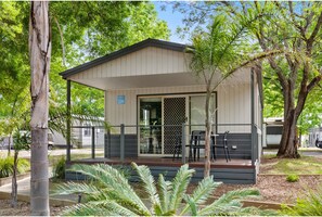 A small, single-story building with a covered porch, numbered 229, surrounded by trees and greenery. - Discovery Parks - Lake Hume, Victoria (Ebden)