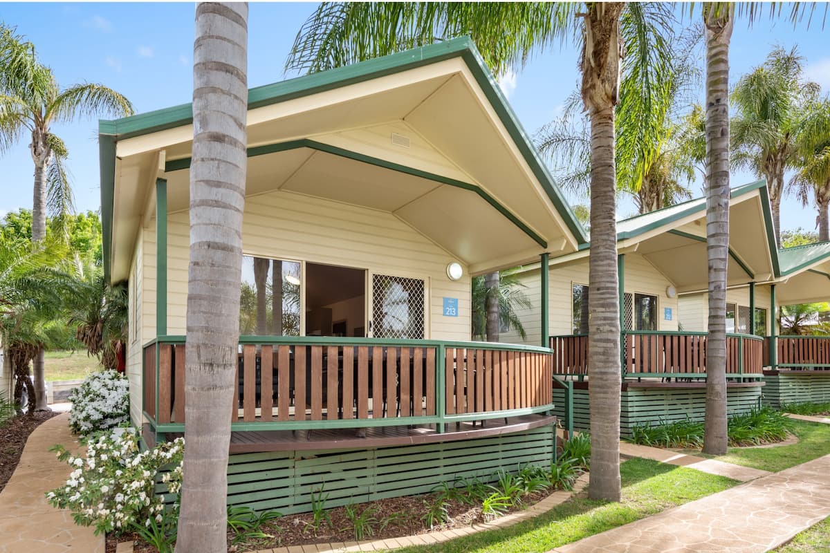 A row of single-story buildings with green railings and a covered porch area.