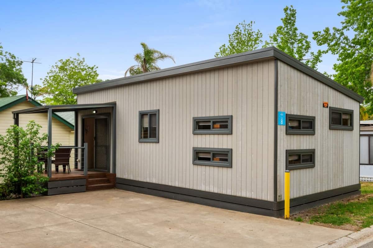 A small, single-story building with a flat roof, a door, and multiple windows.