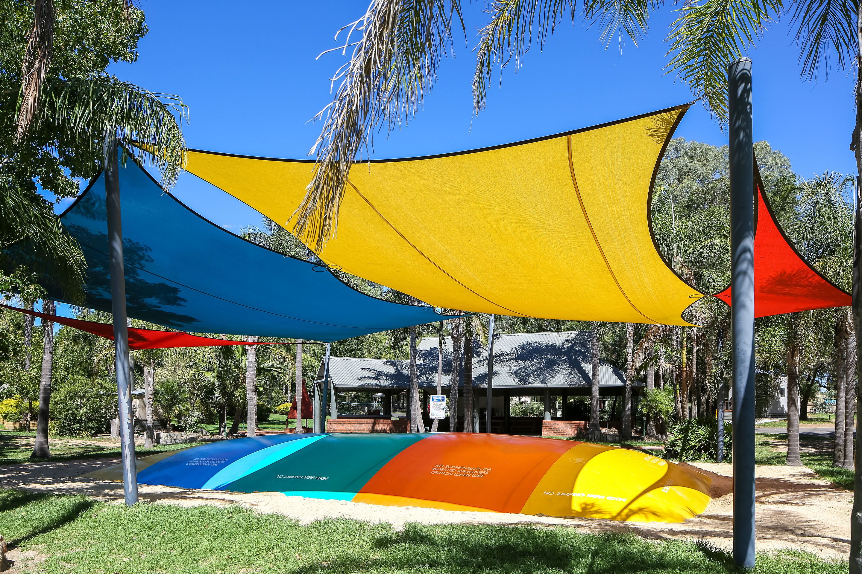 Un parque infantil con mallas de seguridad de colores y un edificio al fondo.