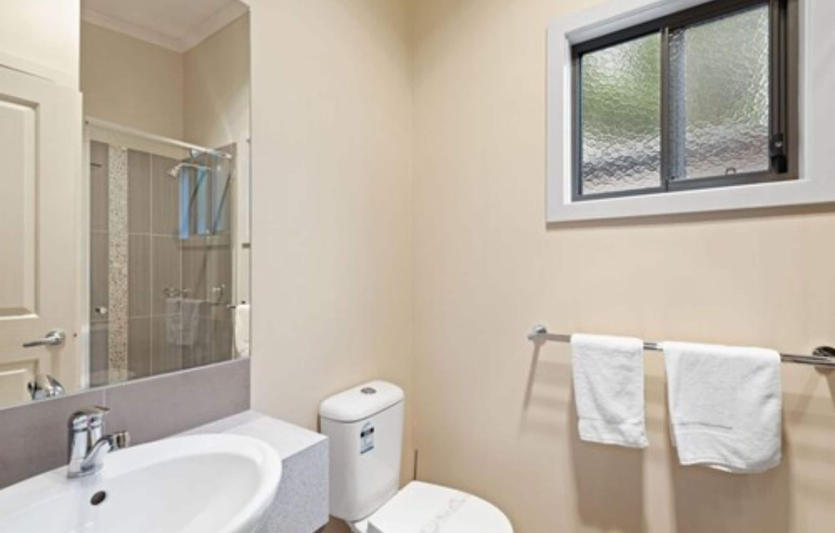 A bathroom with a sink, toilet, and a window.