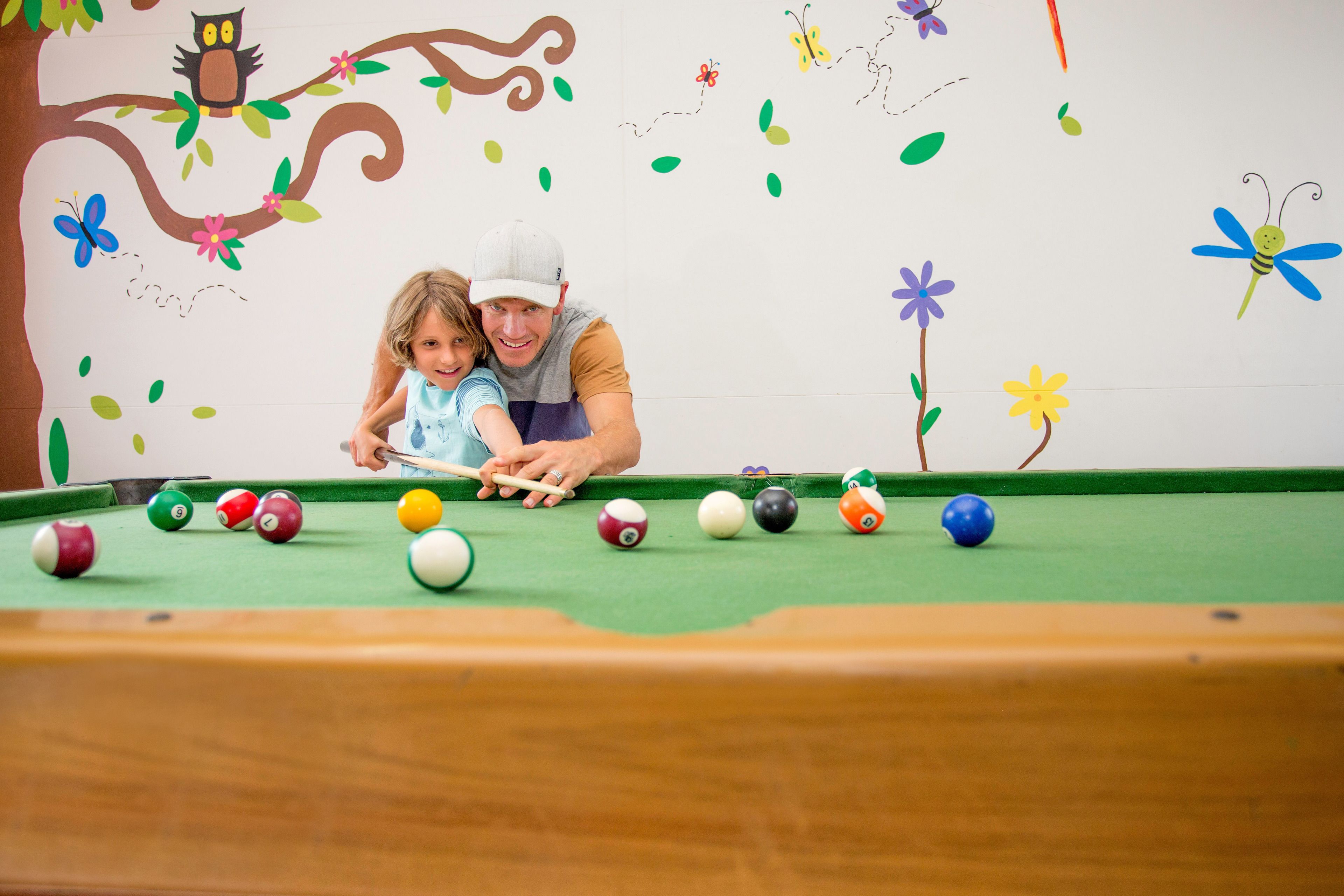 Een biljart met ballen en een kind dat speelt.