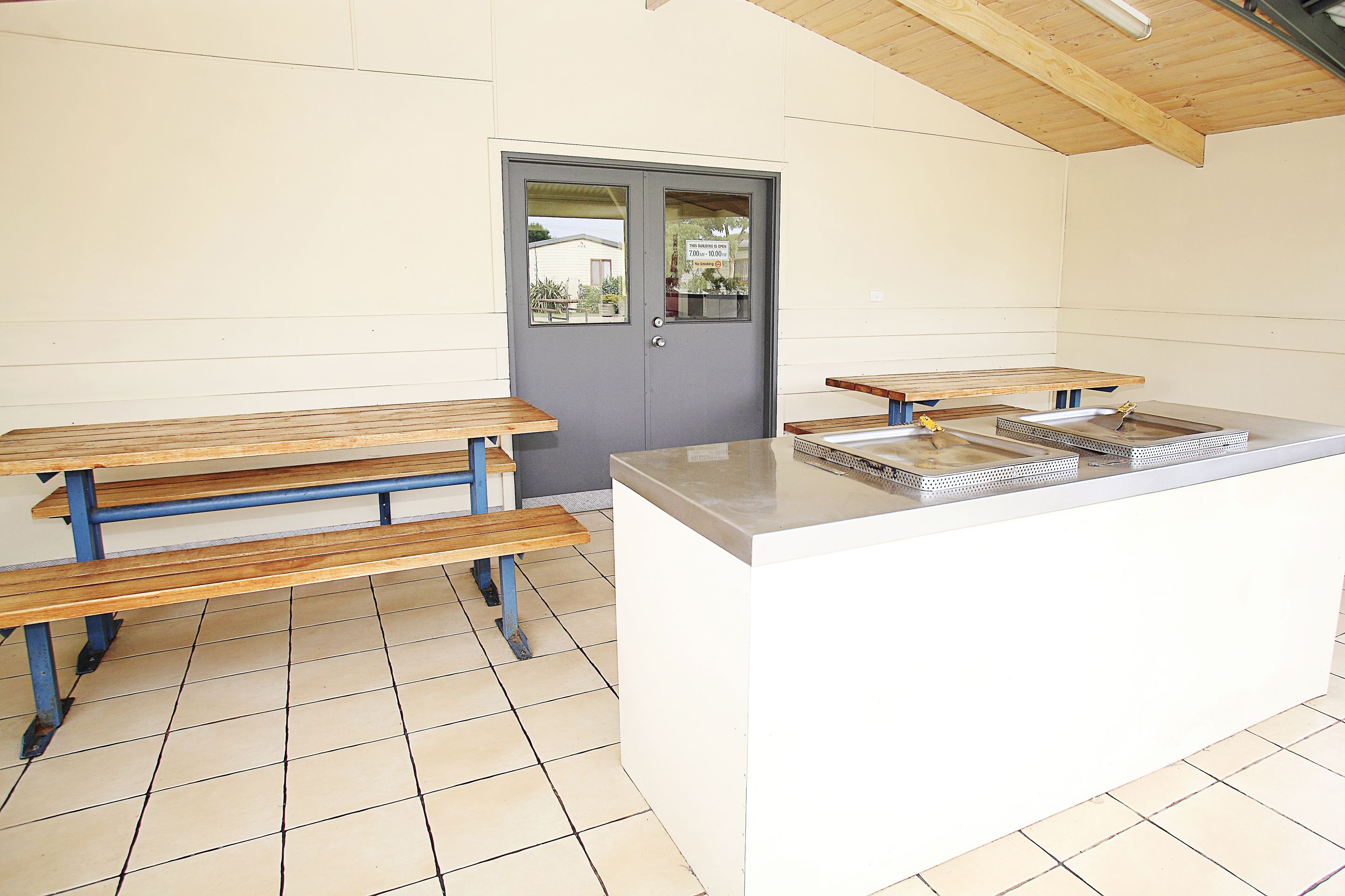 Une cuisine moderne et épurée, avec des bancs en bois et un îlot central doté d’un évier.