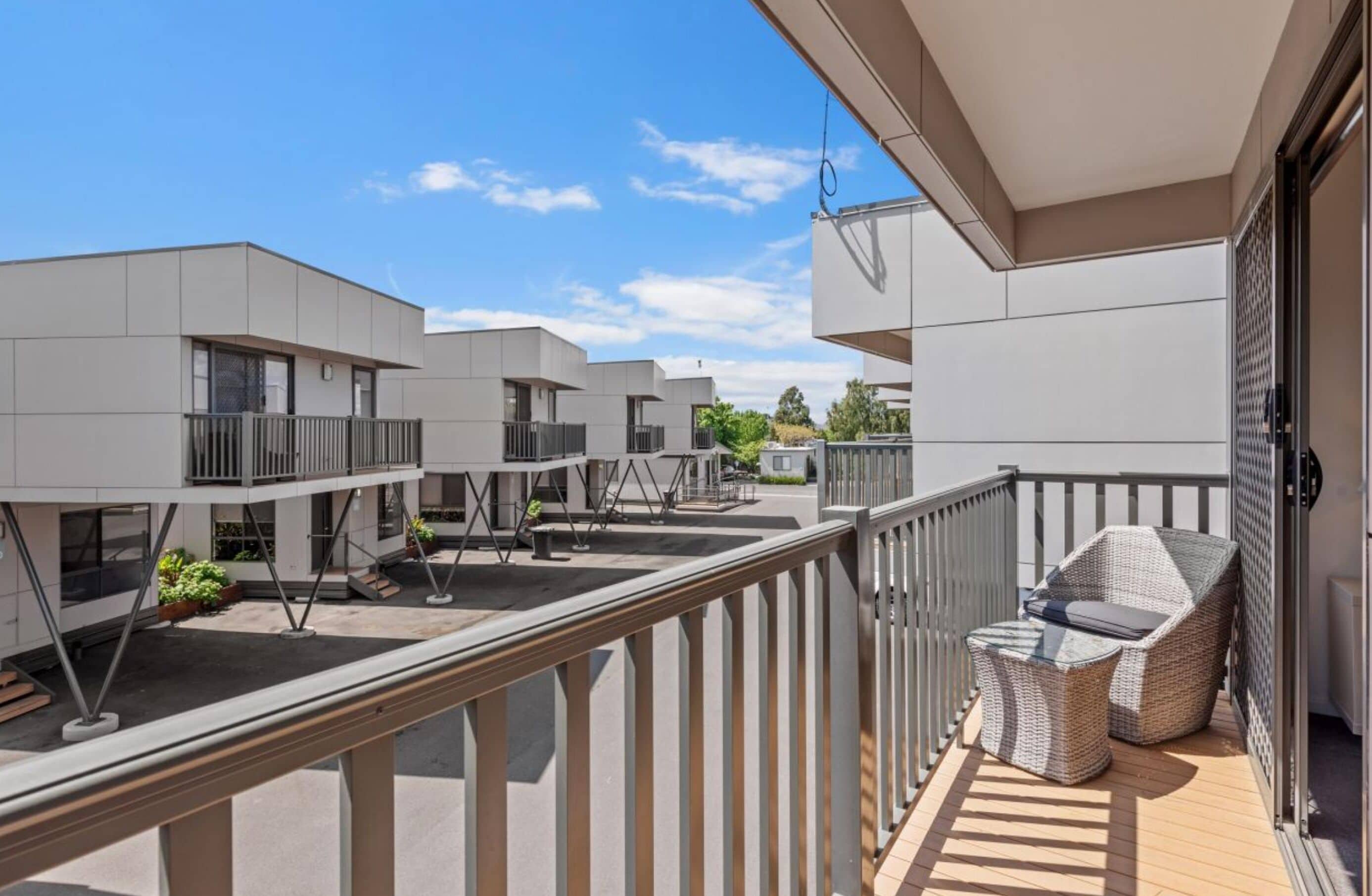 Un bâtiment moderne doté d’un balcon aménagé avec du mobilier d’extérieur.