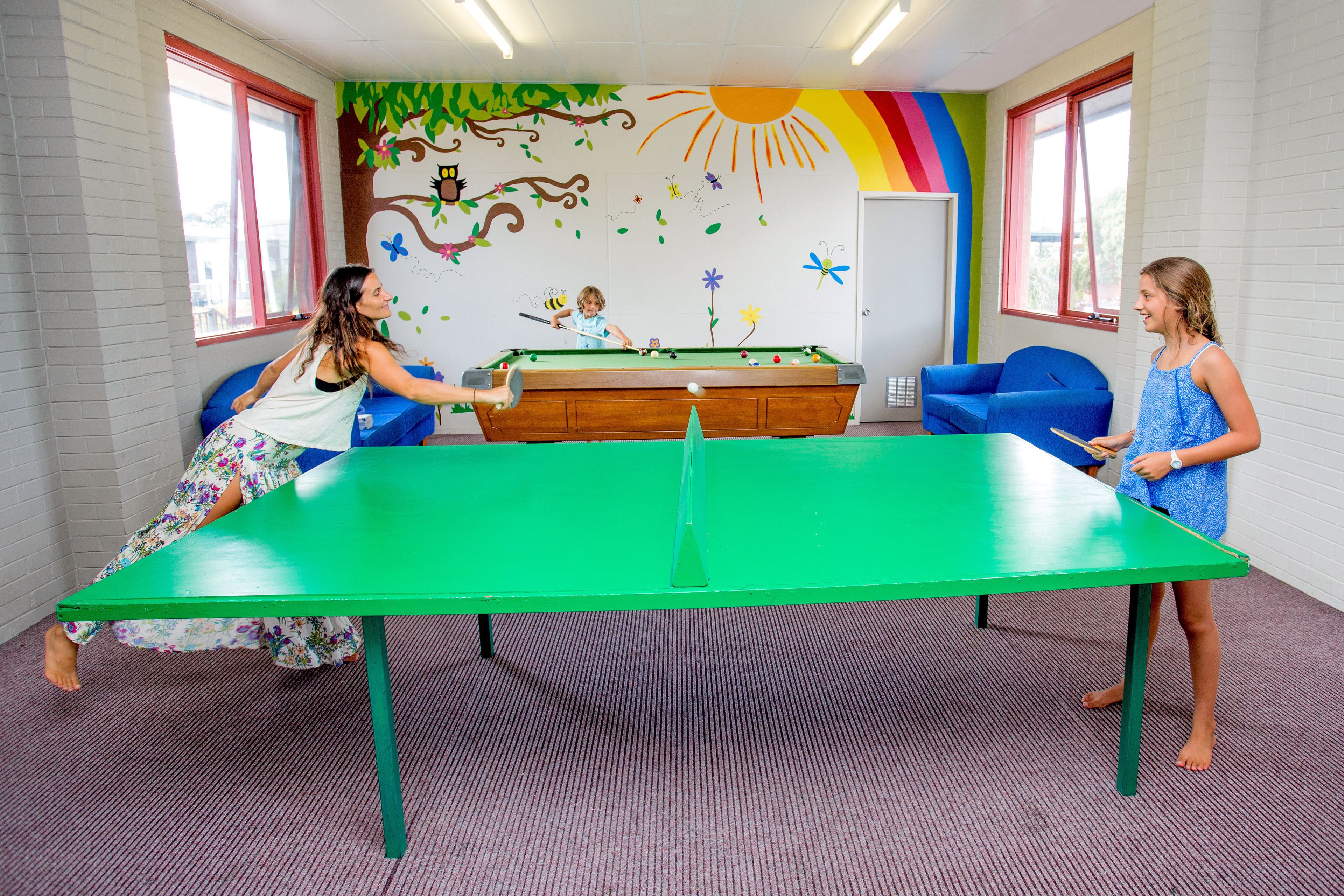 Una habitación con mesa de billar, dos sillas y un mural colorido en la pared.