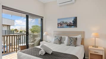 Habitación de hotel con una cama, dos mesitas de noche, una ventana con vistas al exterior y un equipo de aire acondicionado en la pared.