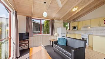 A cozy cabin interior with a living area, a kitchen, and a balcony.