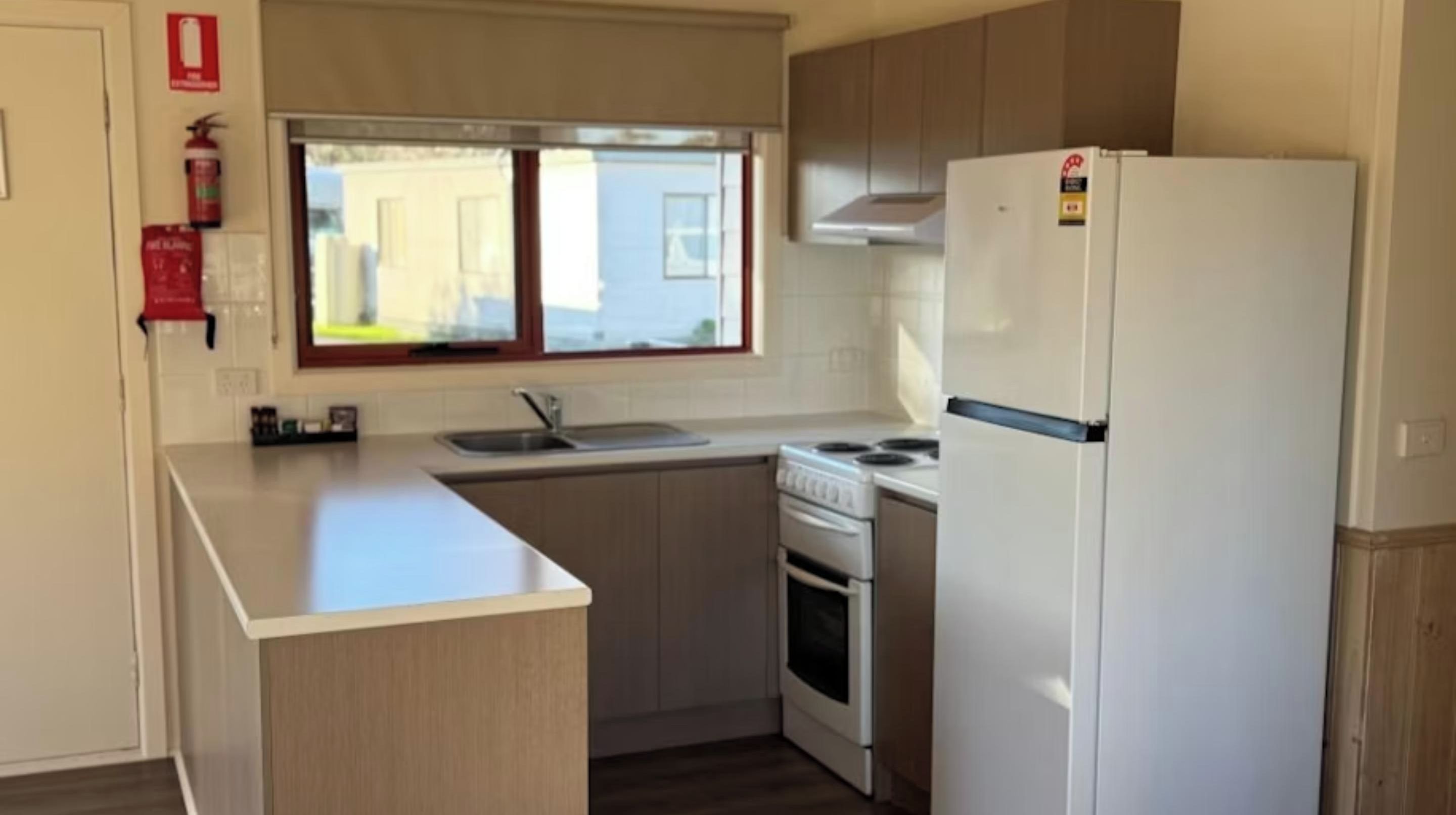 Una cocina compacta con un refrigerador, estufa y pileta blancos.