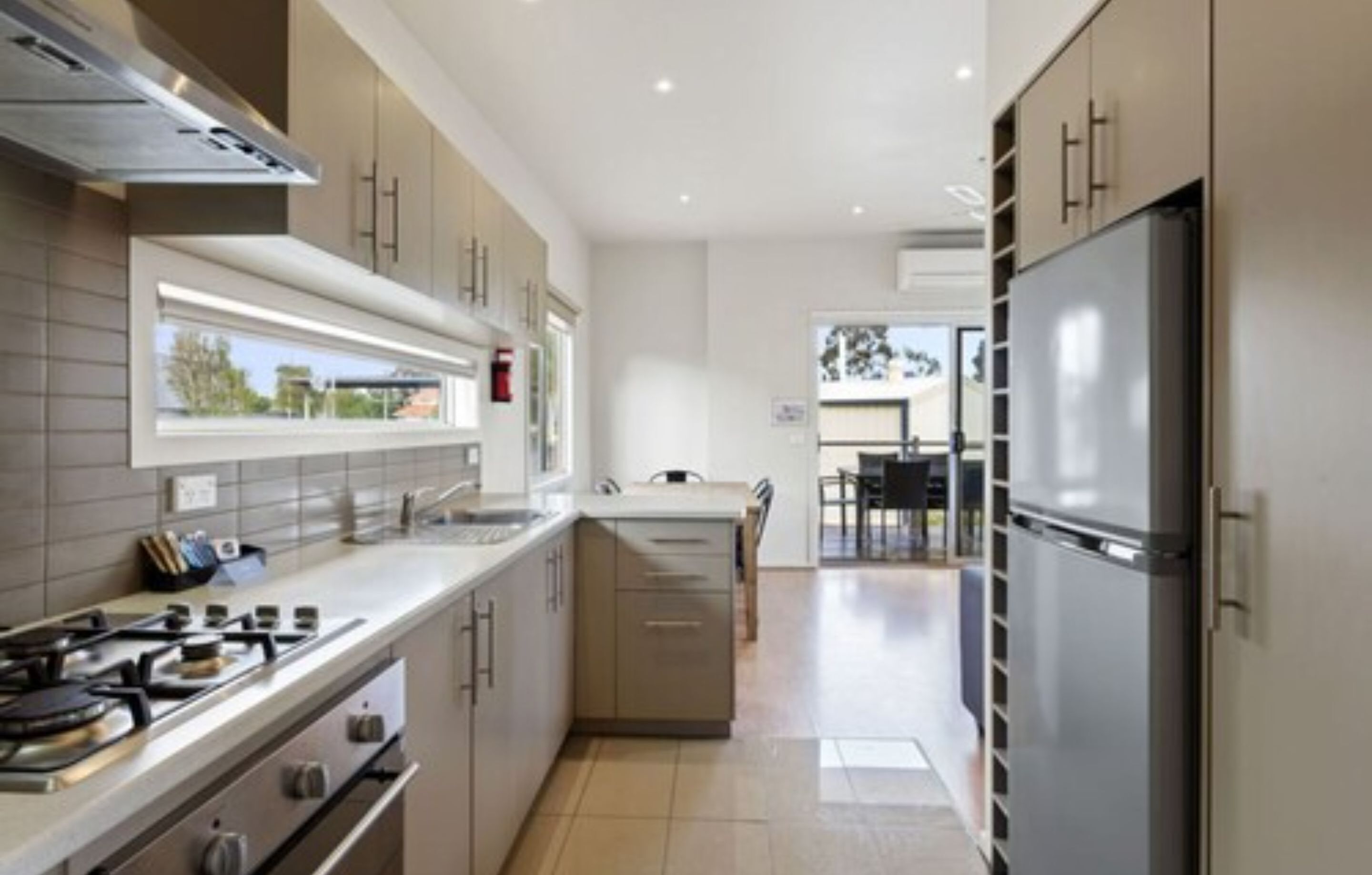 A modern kitchen with a stove, sink, and refrigerator.