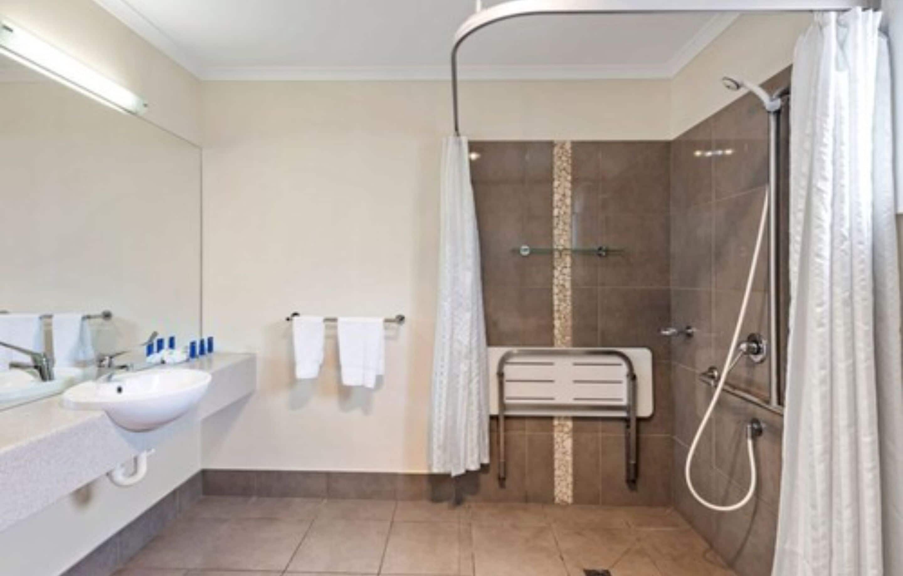 A modern bathroom with a shower, a sink, and a towel rack.
