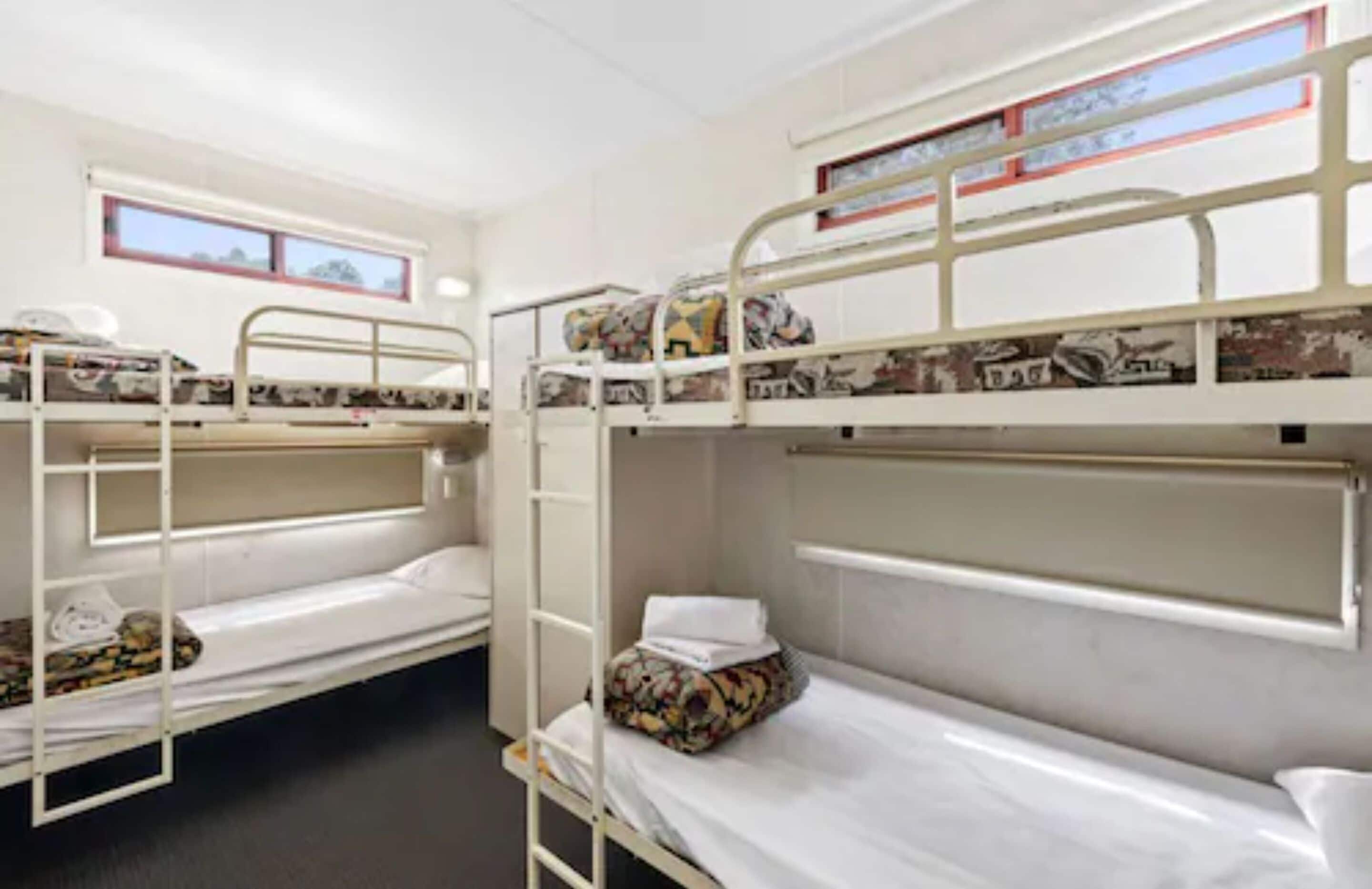A room with bunk beds, a window, and a small table.