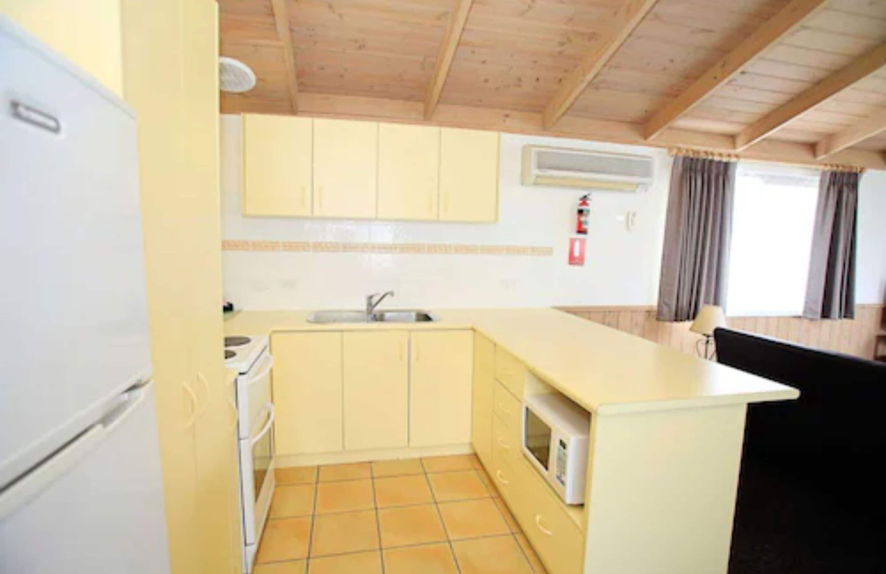 A compact kitchen with a sink, stove, and microwave.