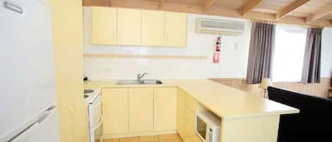 A compact kitchen with a sink, stove, and microwave.