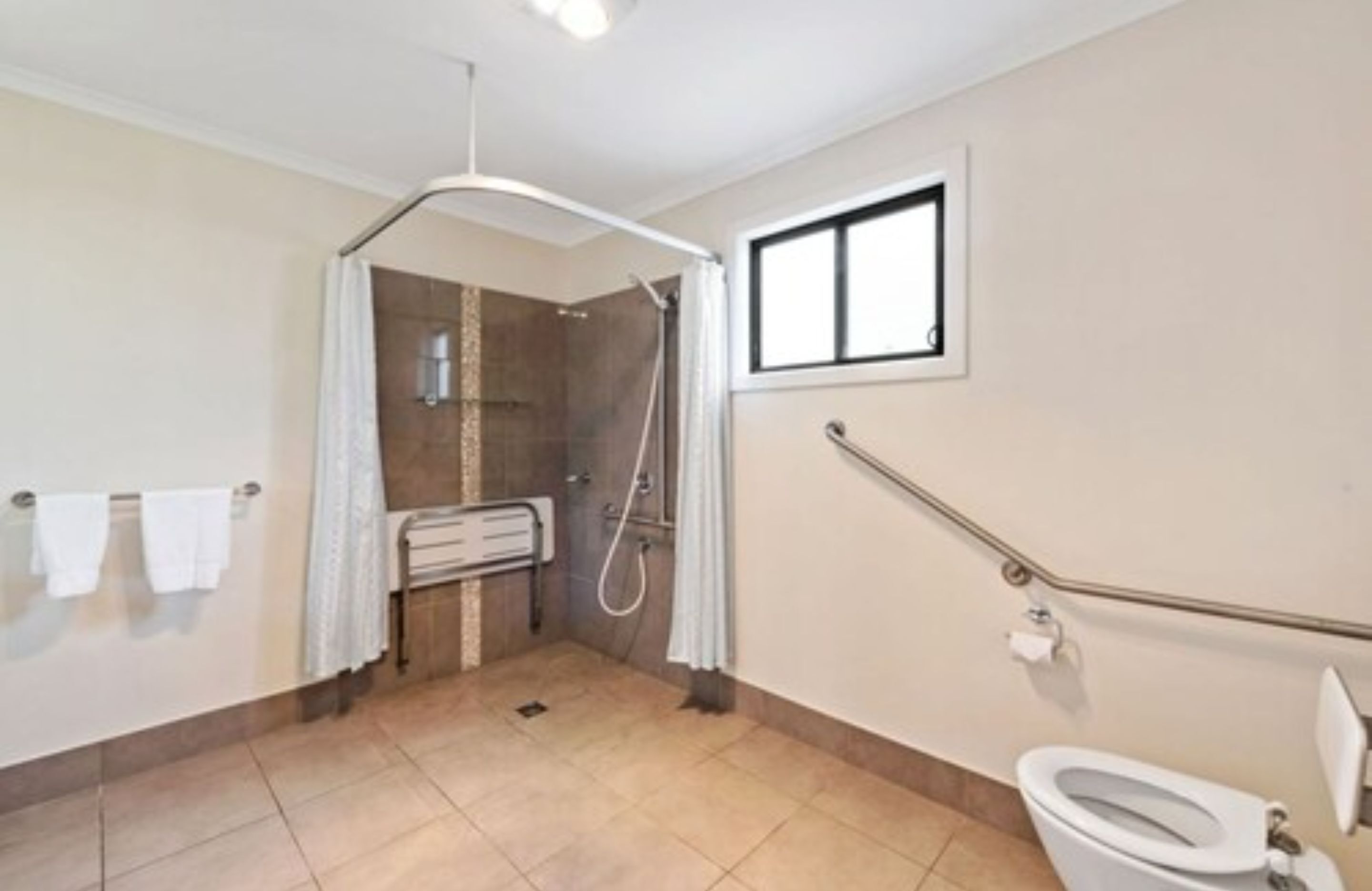 A bathroom with a shower, toilet, and a window.