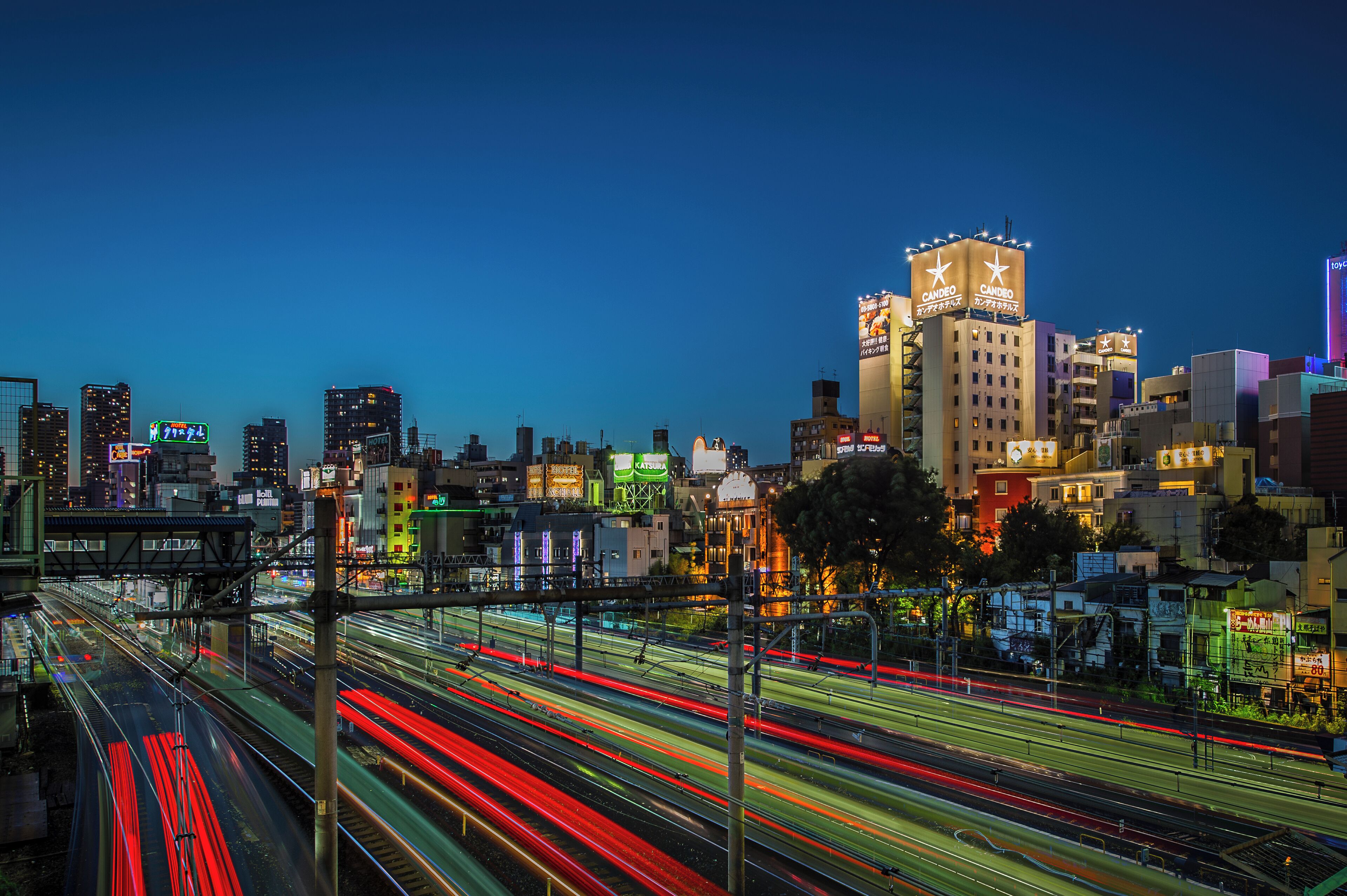 A cityscape at night with illuminated buildings and a busy highway with light trails.