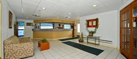 A lobby with a reception desk, a sofa, a coffee table, and a door with a Visa sign.