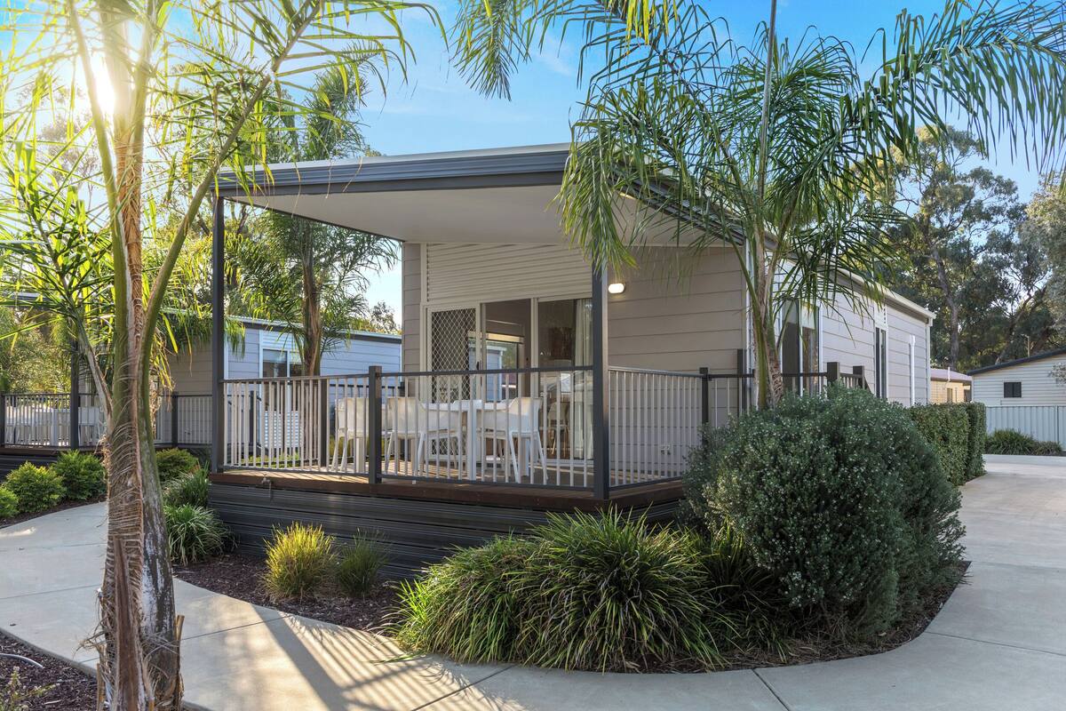 A modern single-story house with a covered porch, a small deck, and a well-maintained garden.