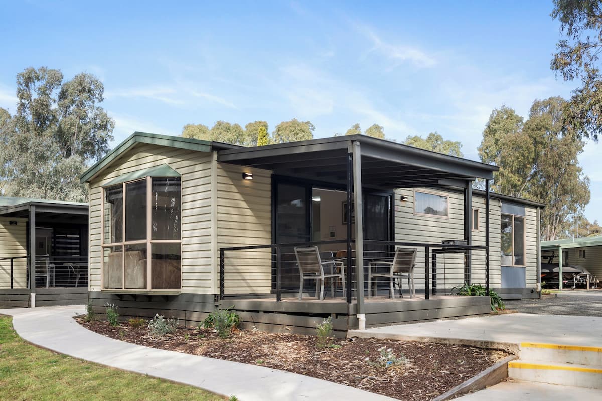 A single-story mobile home with a covered porch and a small deck area.