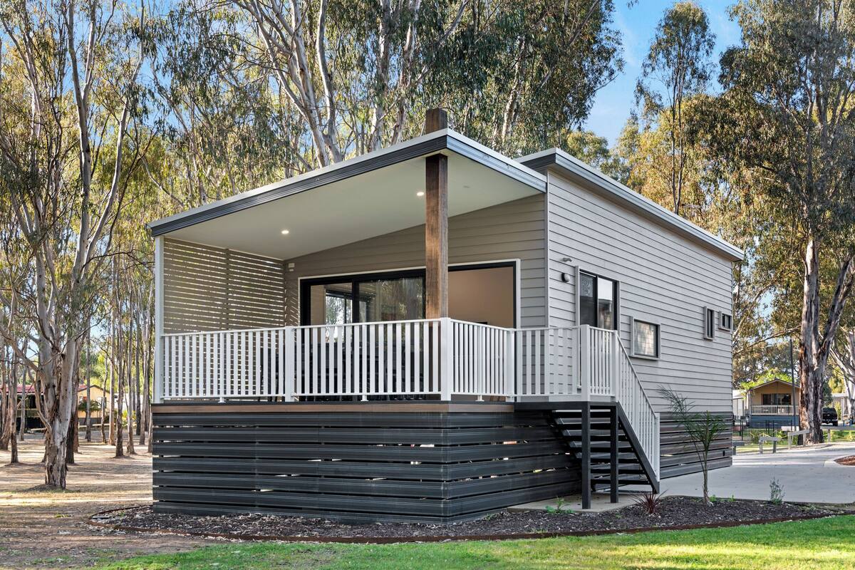 A modern single-story house with a covered porch, a staircase leading to the entrance, and a small garden area.