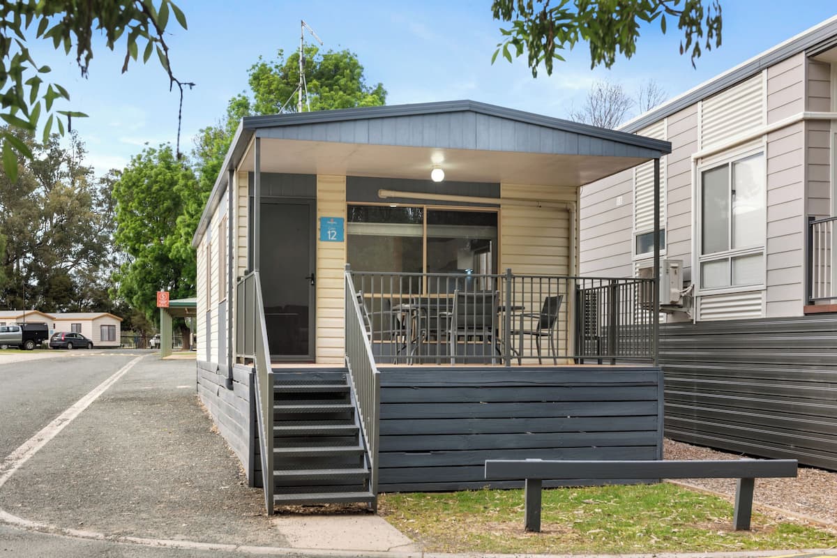 A small building with a covered entrance, a staircase leading up, and a bench outside.