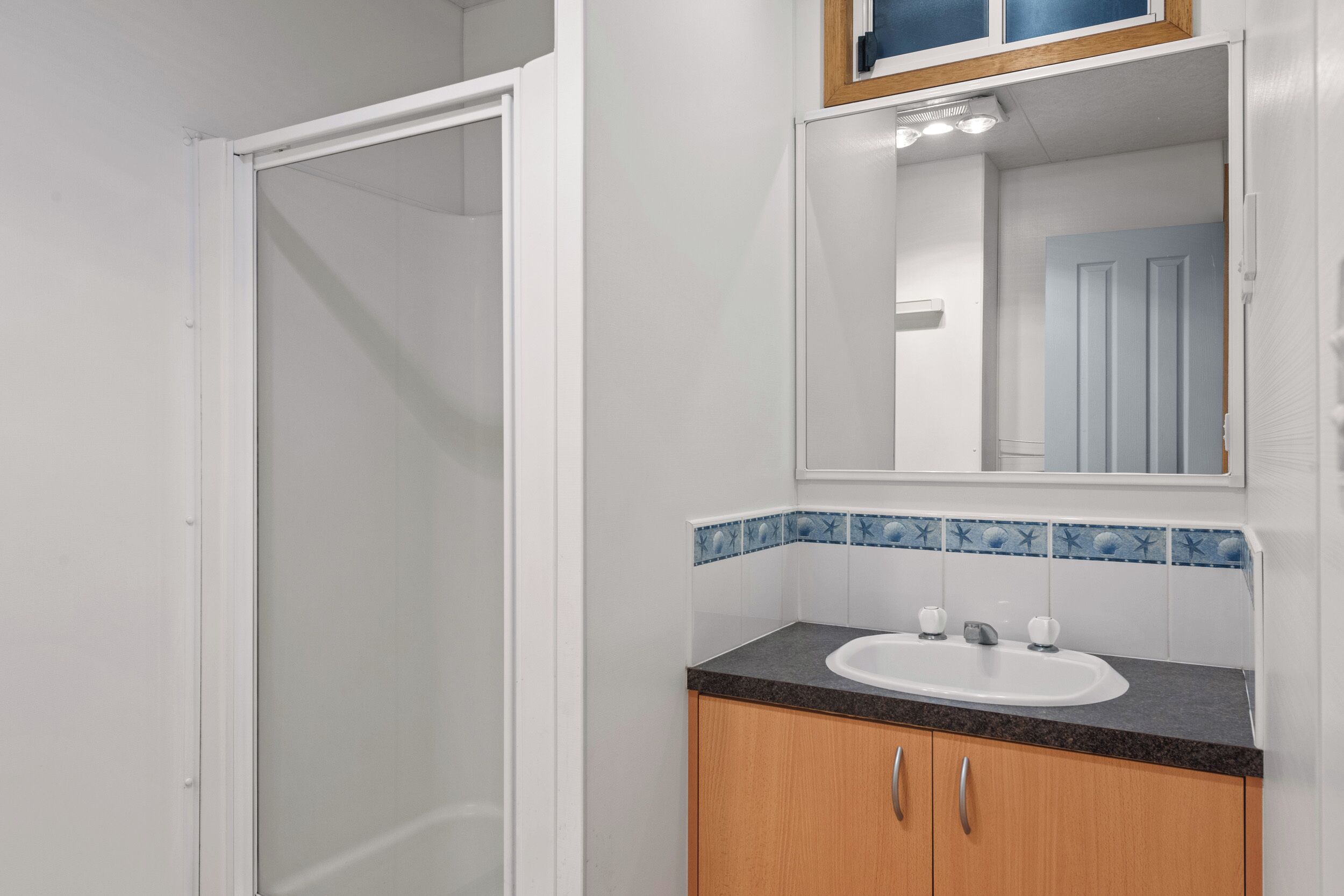 Un bagno con doccia, lavandino e specchio.