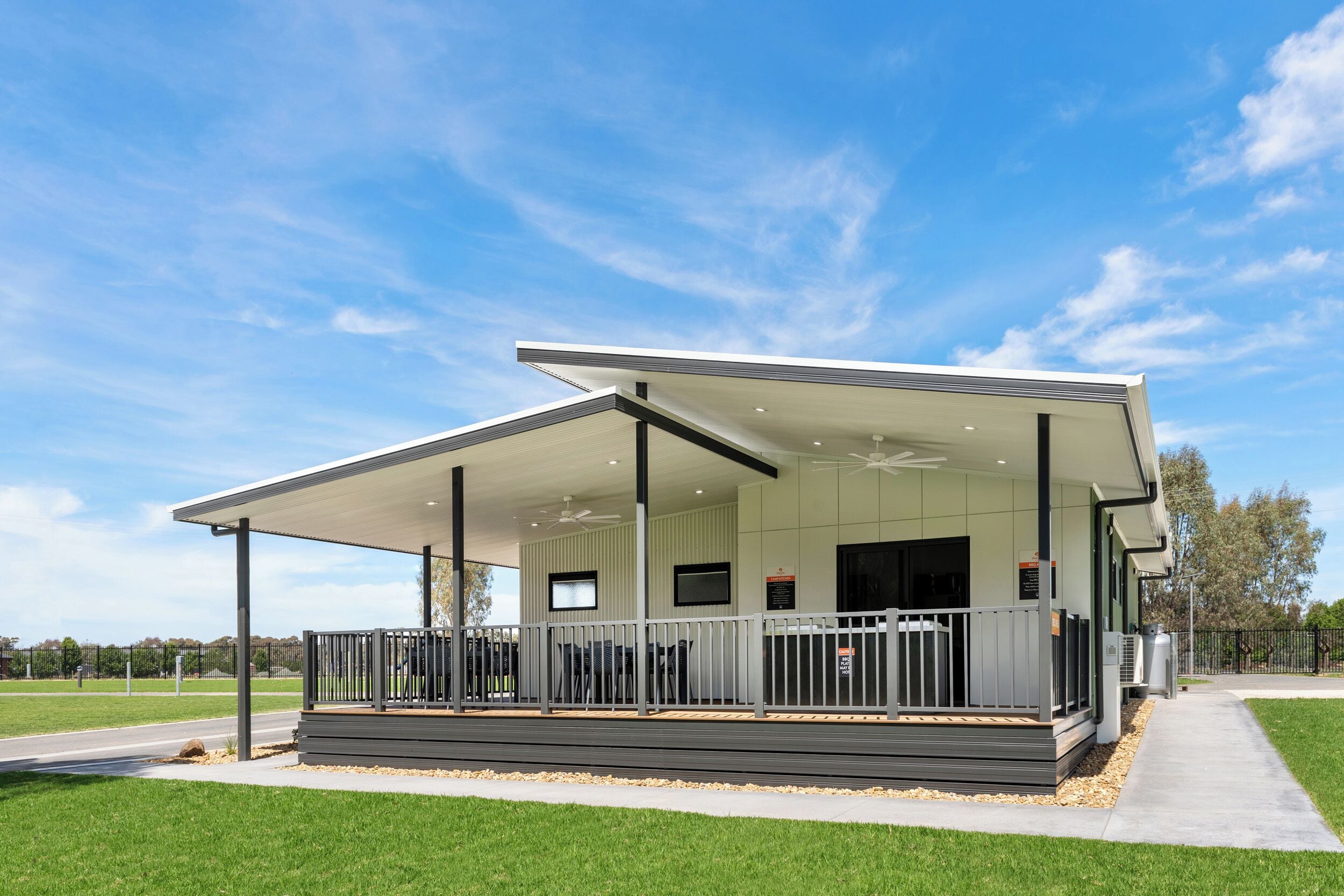 A modern building with a covered outdoor area, a flat roof, and a large window.