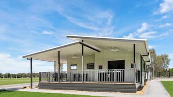 A modern building with a covered outdoor area, a flat roof, and a large window.