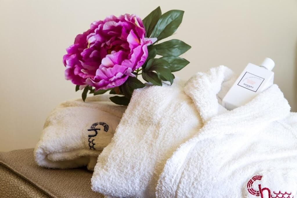 Une serviette, une bouteille et une fleur rose sur une surface.